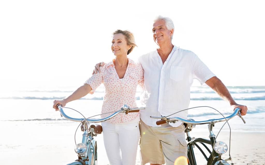 Zwei ältere Menschen mit Fahrrädern am Strand