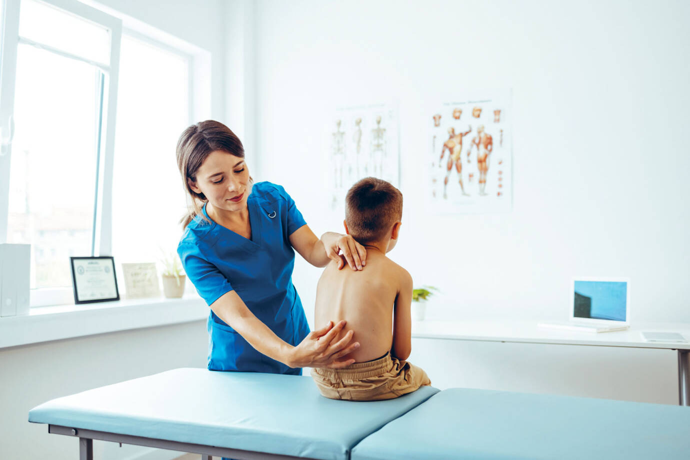 physical therapist examining boy's spine