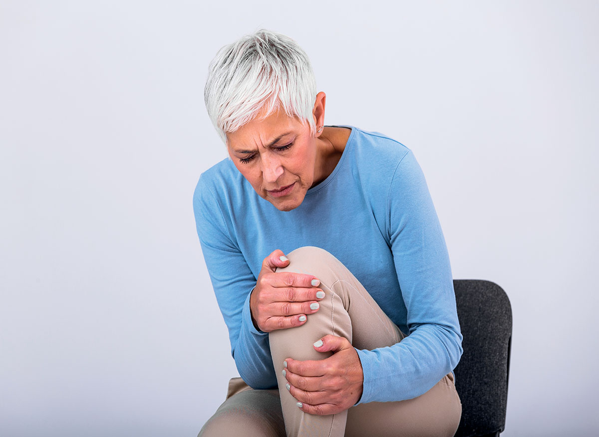 senior woman holding the knee with pain. old age, health problem and people concept senior woman suffering from pain in leg at home. elderly woman suffering from pain in knee at home