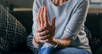 cropped shot of an unrecognizable woman sitting alone at home and suffering from arthritis in her hands